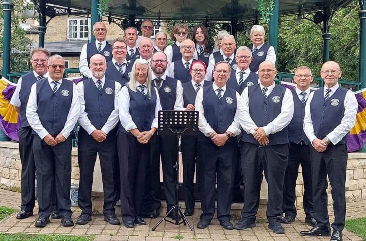Full band image of Dodworth Colliery Miners Welfare band stood in front of Wetherby bandstand.